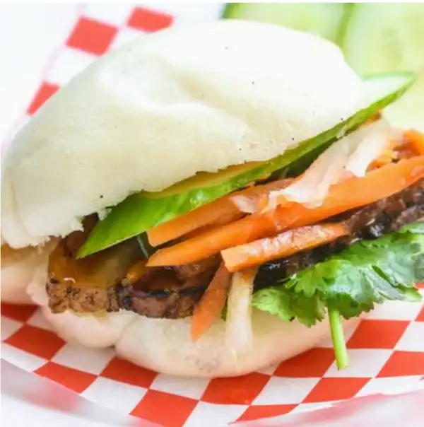 A bun with meat, sliced carrots, and lettuce