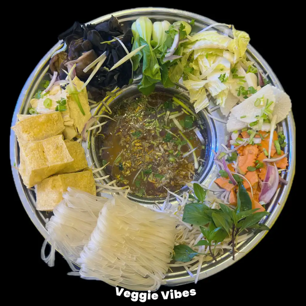 A plate of veggies and tofu with pho in the middle
